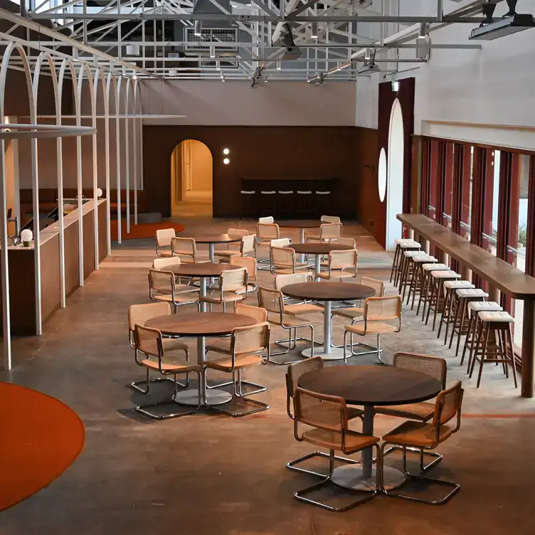 The interior of Yellow Matter Brewing, showing stools set up by a counter at the windows and round tables in the centre.