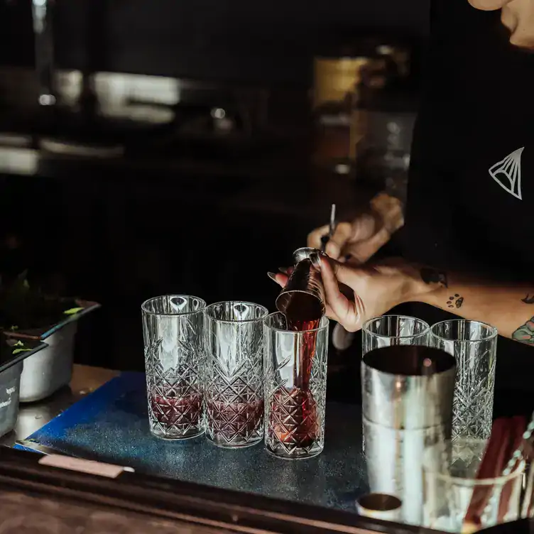 A bartender pours shots into small thin glasses at Double Rainbow Bar & Eating House, one of the best bars in Perth.