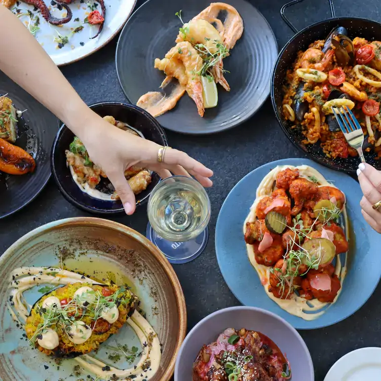 Four Points by Sheraton Perth1.webp: Diners reach across a table filled with pasta, pizza and other dishes at The Best Brew Bar & Kitchen, one of the best bars in Perth.