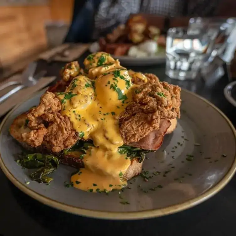 Eggs benedict on top of fried chicken and bacon on a table at Todd and Pup, which offers one of Brisbane’s best pub lunches.