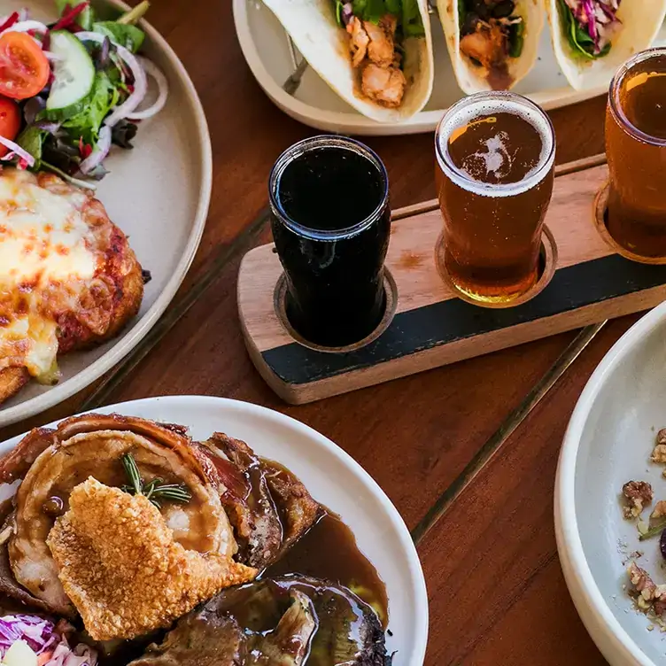 A table with a flight of different beers, a chicken parmigiana and tacos served at Sandgate Post Office Hotel.