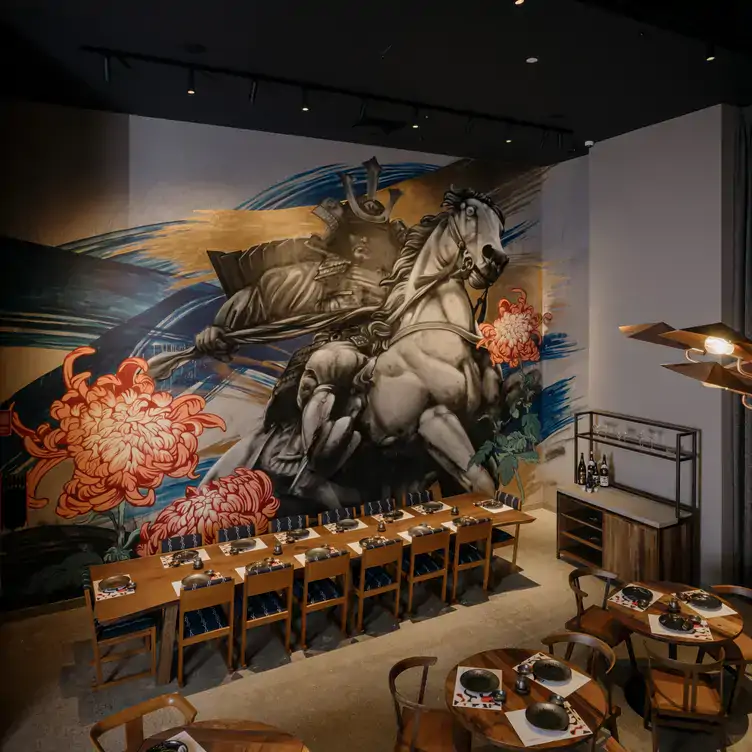 A long table in front of a large mural of a samurai riding a horse surrounded by large flowers at Izakaya Público, one of the best pubs in Brisbane