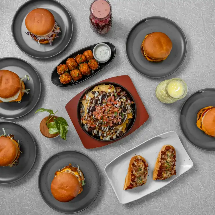 A table laid out with burgers, nachos and cocktails served at Two-Bit Villains, one of the best pubs in Adelaide.