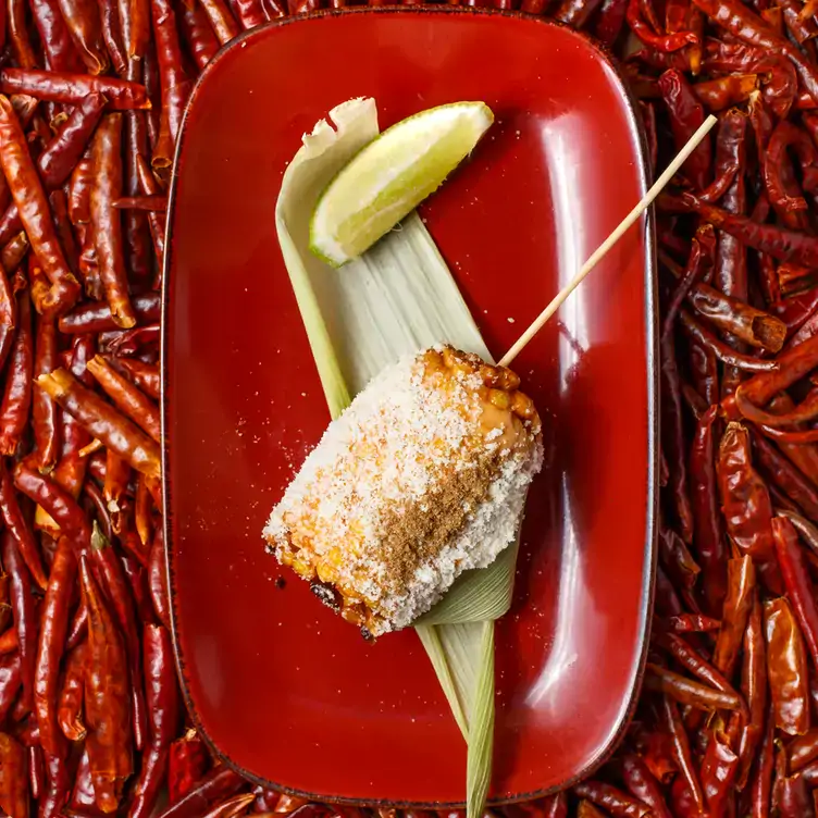 Mexican snack on a leaf on a red plate with a lime wedge, over a bed of dried red chillies, served at Bodega Underground, one of the best restaurants in Melbourne CBD.