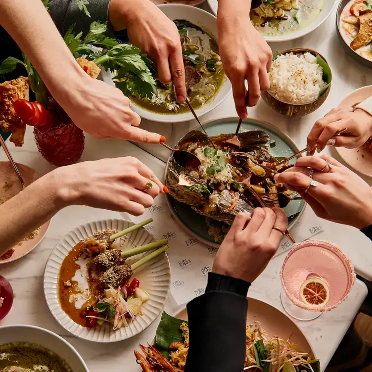 Diners reach for a sharing dish over a table