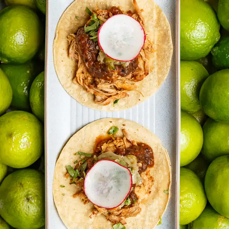 Two meat tacos sit on a background of lime at Bodega Underground