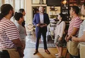 Scene depicts a restaurant setting. The restaurant team of 5 are having a meeting