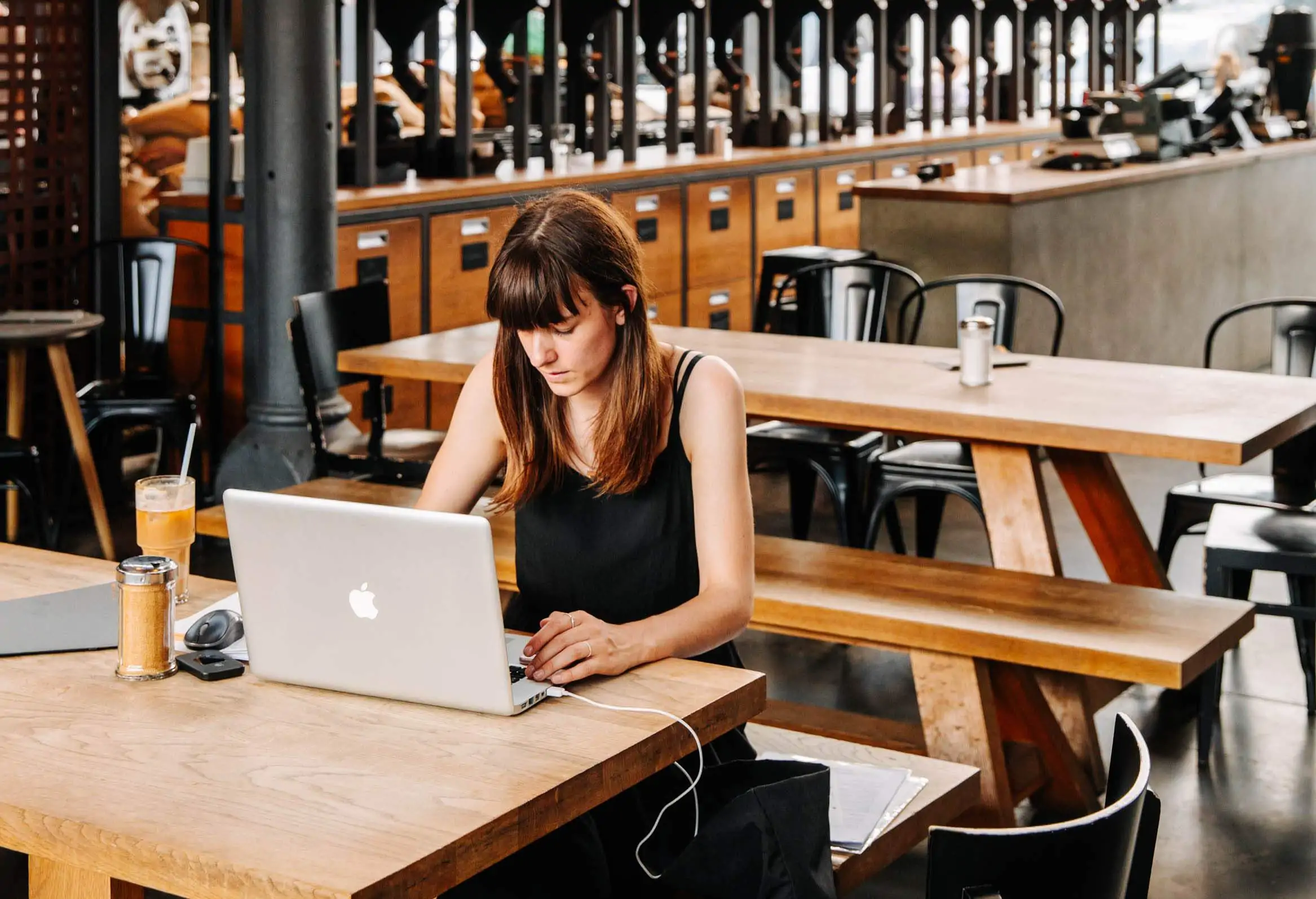 Image depicts a person in a restaurant working on their laptop