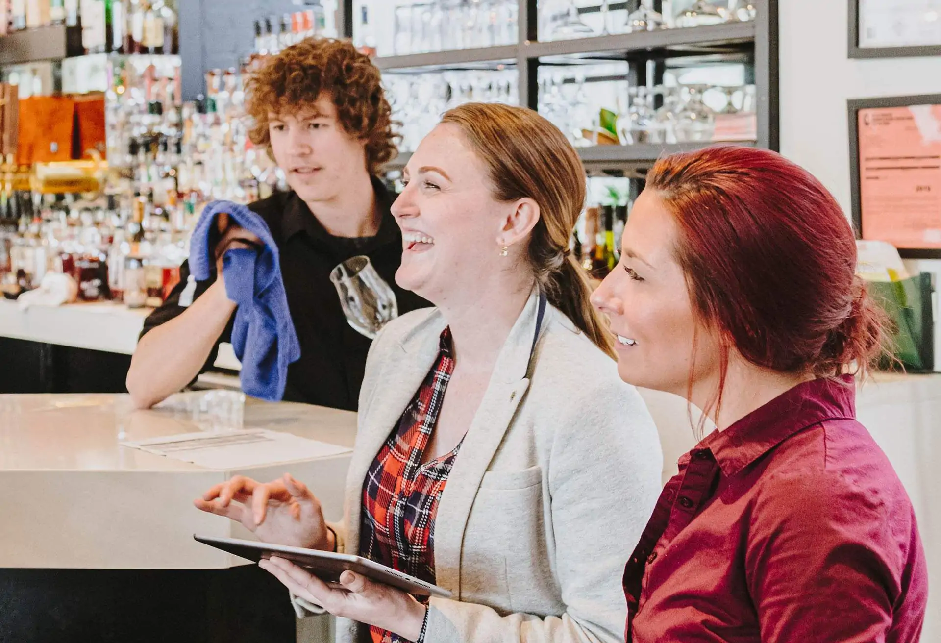 Three restaurant workers in a restaurant scene, one of them is holding a tablet